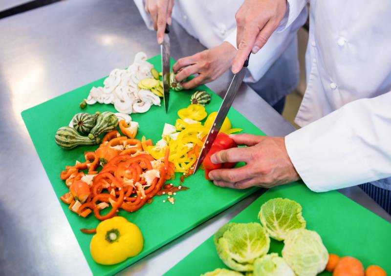 chefs cutting produce in kitchen