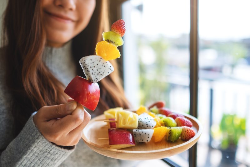 girl eating precut fruit skewers